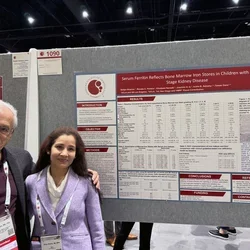 Scientific poster with Sharma Shilpa and Tomas Ganz standing next to it